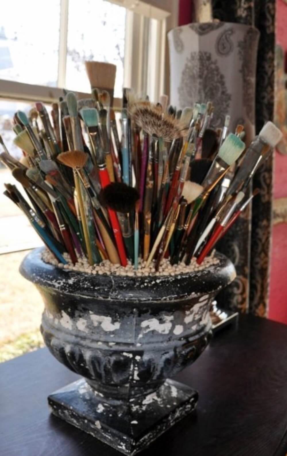 A collection of artist paint brushes in a vintage container, located in Danna Donovan's studio